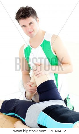 Joven fisioterapeuta masculino comprobar la rodilla de una mujer