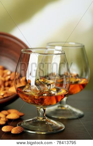 Dessert liqueur Amaretto with almond nuts, on wooden table, on light background