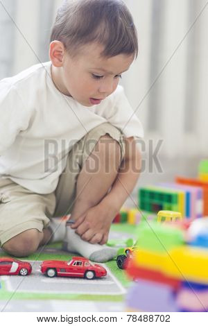 Portrait Of Little Caucasian Boy Playing With Toys Indoors