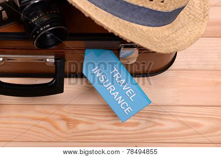 Suitcase and tourist stuff with inscription travel insurance on wooden background
