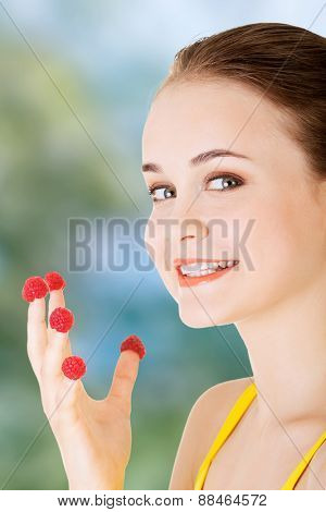 Cacuasian woman with raspberries on fingers.