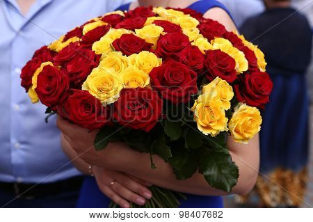 red and yellow roses bouquet in the hands