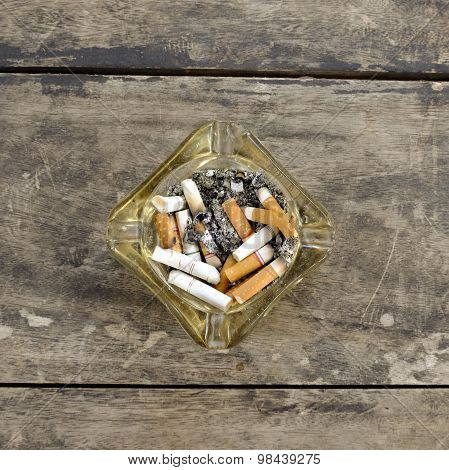 Ashtray Full Of Butt Cigarettes On Wooden Background