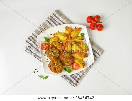 plate of roasted potatoes and fried meatballs on checkered dishtowel