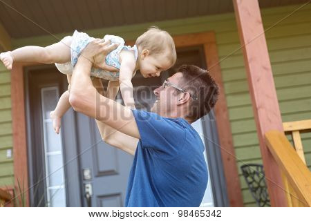 father and daughter play in front of the house