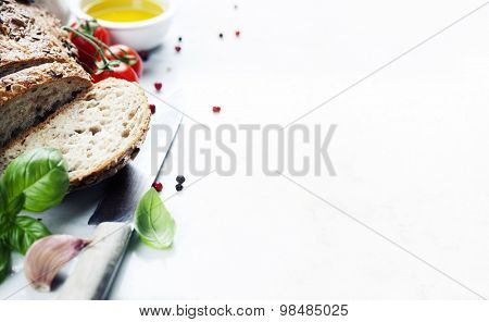 Tomato, bread, basil and olive oil on white marble background. Italian cooking, healthy food or vegetarian concept