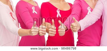 healthcare, people, gesture and medicine concept - close up of women in blank shirts with pink breast cancer awareness ribbons showing thumbs up over white background