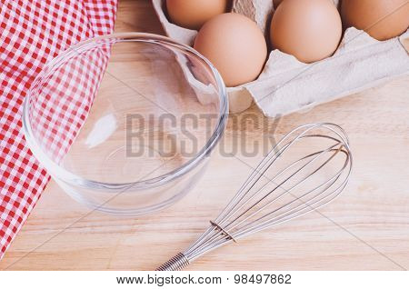 Cookies ingredients. Bowl, flour, eggs, jar of milk, eggbeater,eggshells and red napkin