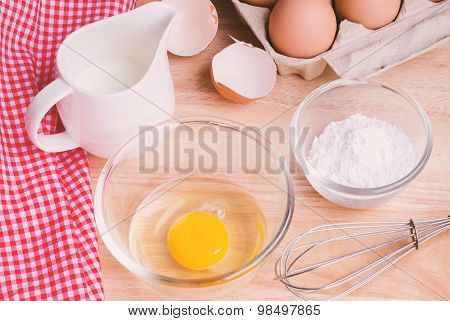 Cookies ingredients. Bowl, flour, eggs, jar of milk, eggbeater,eggshells and red napkin