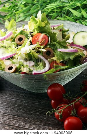 Bowl Of Salad With Vegetables And Greens On Wooden Table