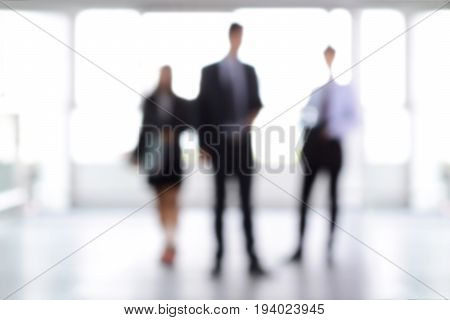 Blurred business people standing in building hall can be used as background