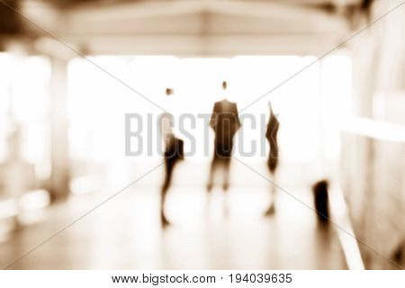 Blurred business people standing in building hall sepia tone - can be used as abstract background
