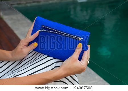 Luxury fashion snakeskin python wallet in woman hands outdoors, shoot near the swimming pool.