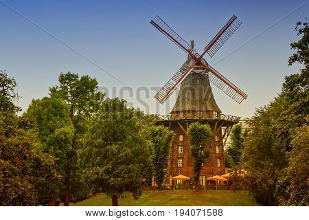 old wind mill among the green trees in the Park toned