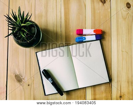 Sketch book on the table Open sketch book is lying on a wooden table Top view of artist workplace Modernt workplace of creative people: sketch book, markers and green plant