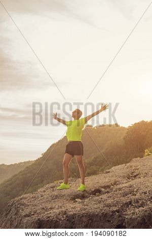 Success of a man after jogging / exercising on a clif near the sea / ocean.