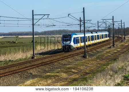 Flevoland the Netherlands - March 26 2016: Dutch sprinter train traveling through countryside.