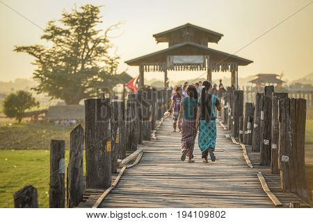 Unidentified couple Burmese woman walk on U Bein Bridge at sunset the oldest and longest teak bridge (Wooden footbridge) in the world at Amarapura township near Mandalay Myanmar