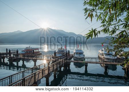 NANTOU TAIWAN - FEBRUARY 13 2017 : travel boats at pier and beautiful sunrise over mountain peak of Sun Moon Lake National Scenic Area popular travel destination in Yuchi Township Nantou Taiwan.