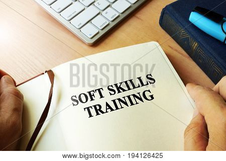Hands holding book with title Soft skills training.