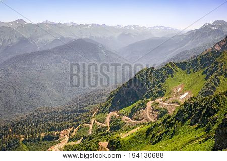 Mountain landscape: steep mountains covered with forests form a deep gorge on the of a mountain winding road with steep turns - a mountain serpentine.
