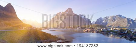 Panorama of Island of Hamnoy, Reine on the Lofoten in northern Norway. The Typical Norwegian fishing village of Reine under midnight sun, blue sky, with the typical rorbu houses.