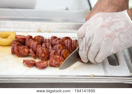 Cooker cutting chorizo sausage pepperoni on white table