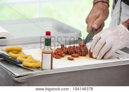 Cooker cutting chorizo sausage pepperoni on white table