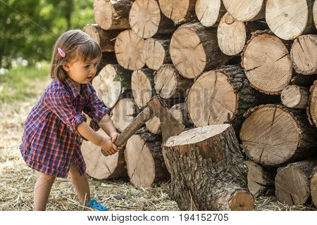 Little girl cuts the tree near the deck woodthe concept of children's recreation