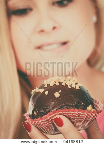 Diet sweets food concept. Woman holding delicious chocolate cupcake with peanut frosting about to take bite