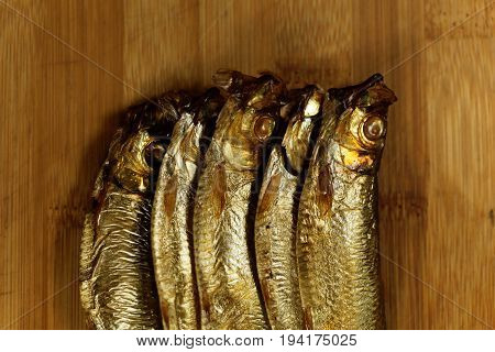 Smoked European sprats Sprattus sprattus on a wooden background.
