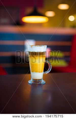 transparent mug with coffee machiato is on the table.