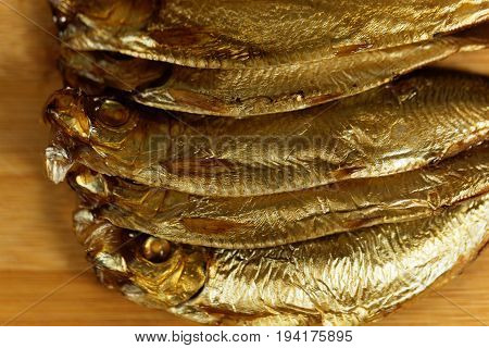 Smoked European sprats Sprattus sprattus on a wooden background.
