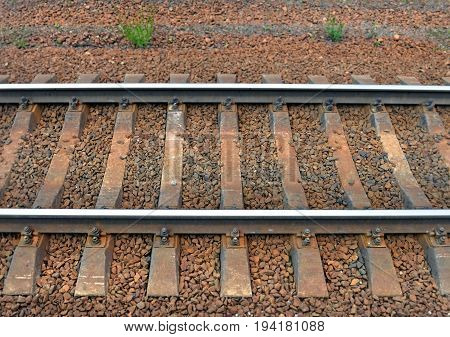 Fragment of railway track. Rails and cross ties. Top view from side. Background.