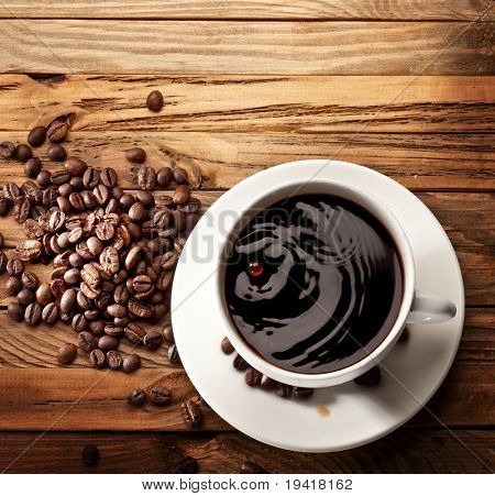 Goccia che cade in una tazza di caffè. Su fondo in legno