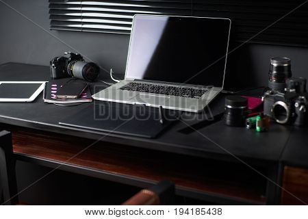 Work space on black table of a photographer or designer with laptop retro camera Stylish home studio concept of hipster . Seleted focus.