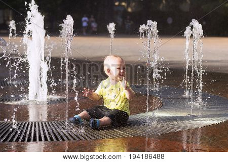 Cute Toddler Playing With Water Streams In Fountain