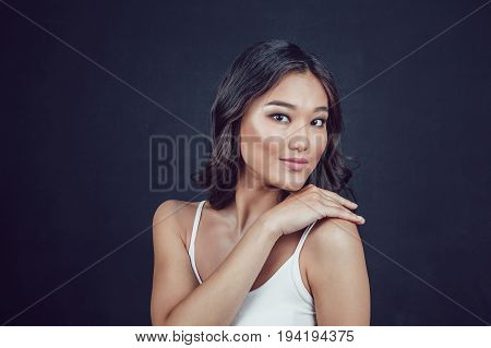 Portrait of a beautiful asian woman with makeup and light curls on black background.