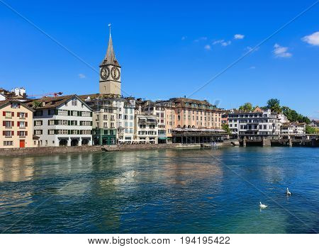 Zurich, Switzerland - 18 June, 2017: old town buildings along the Limmat river, clock tower of the St. Peter Church, Hotel Storchen. Zurich is the largest city in Switzerland and the capital of the Swiss canton of Zurich.
