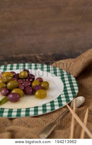 Close up of olives served in plate on wooden table