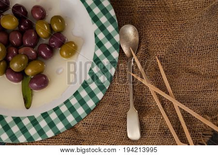 Cropped image of olives served in plate on wooden table