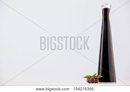 Close up of red olives with oil bottle against white background