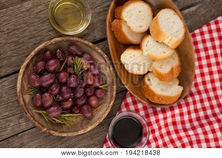 Overhead view of olives and bread in plate  with oil on table