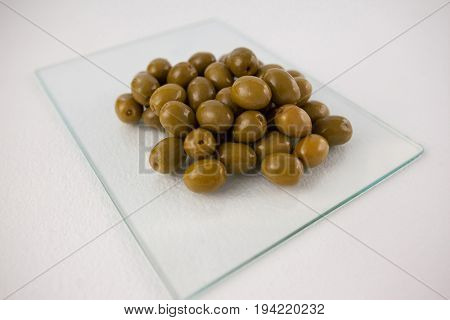 Close up of green olives on glass slab at table