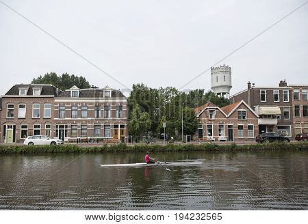 delft netherlands 30 june 2017: delftse schie and woman in canoe in dutch town of delft