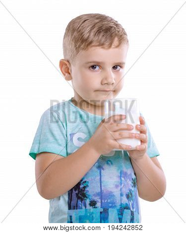 Pensive little child in a blue t-shirt holds a glass of milk. A cute little kid with fresh milk isolated on a white background.
