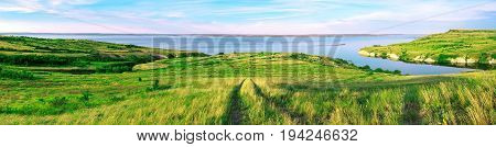 Scenic sea view from top of hills. Beautiful summer background. Amazing landscape with yellow meadows green trees blue sky steep cliffs and picturesque bay. Panoramic photo. Camping rest relax.