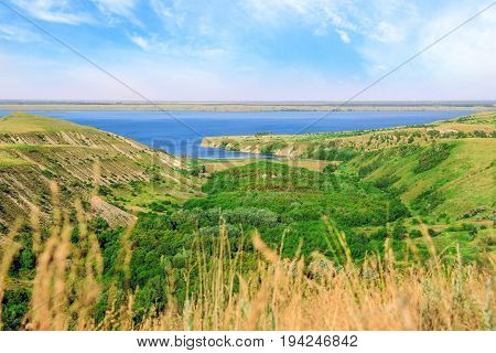 Scenic sea view from top of hills. Beautiful summer background. Amazing landscape with yellow meadows green trees blue sky steep cliffs and picturesque bay. Panoramic photo. Camping and rest.