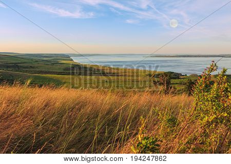 Scenic sea view from top of hills. Beautiful summer background. Amazing landscape with yellow meadows green trees blue sky steep cliffs and picturesque bay. Panoramic photo. Camping rest relax.