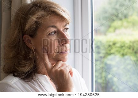 Sad Woman Suffering From Agoraphobia Looking Out Of Window